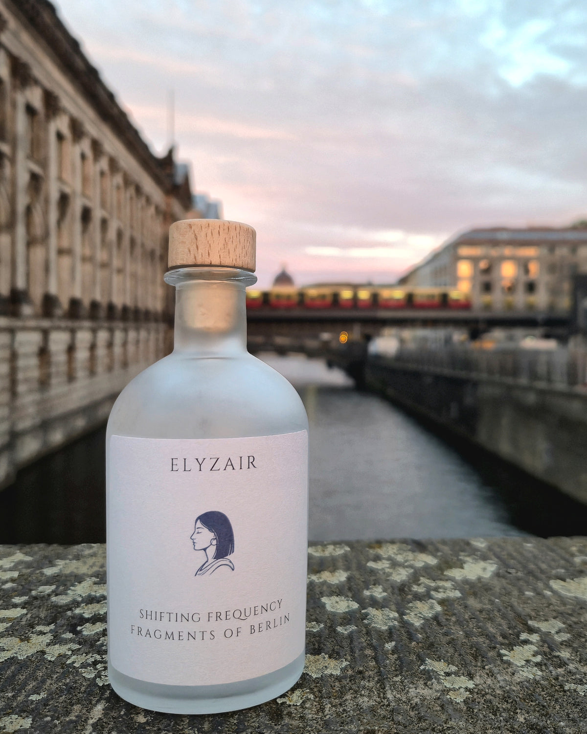 ELYZAIR Shifting Frequency, sealed glass edition of Berlin, on a stone parapet above the river, an S-Bahn crossing at dusk