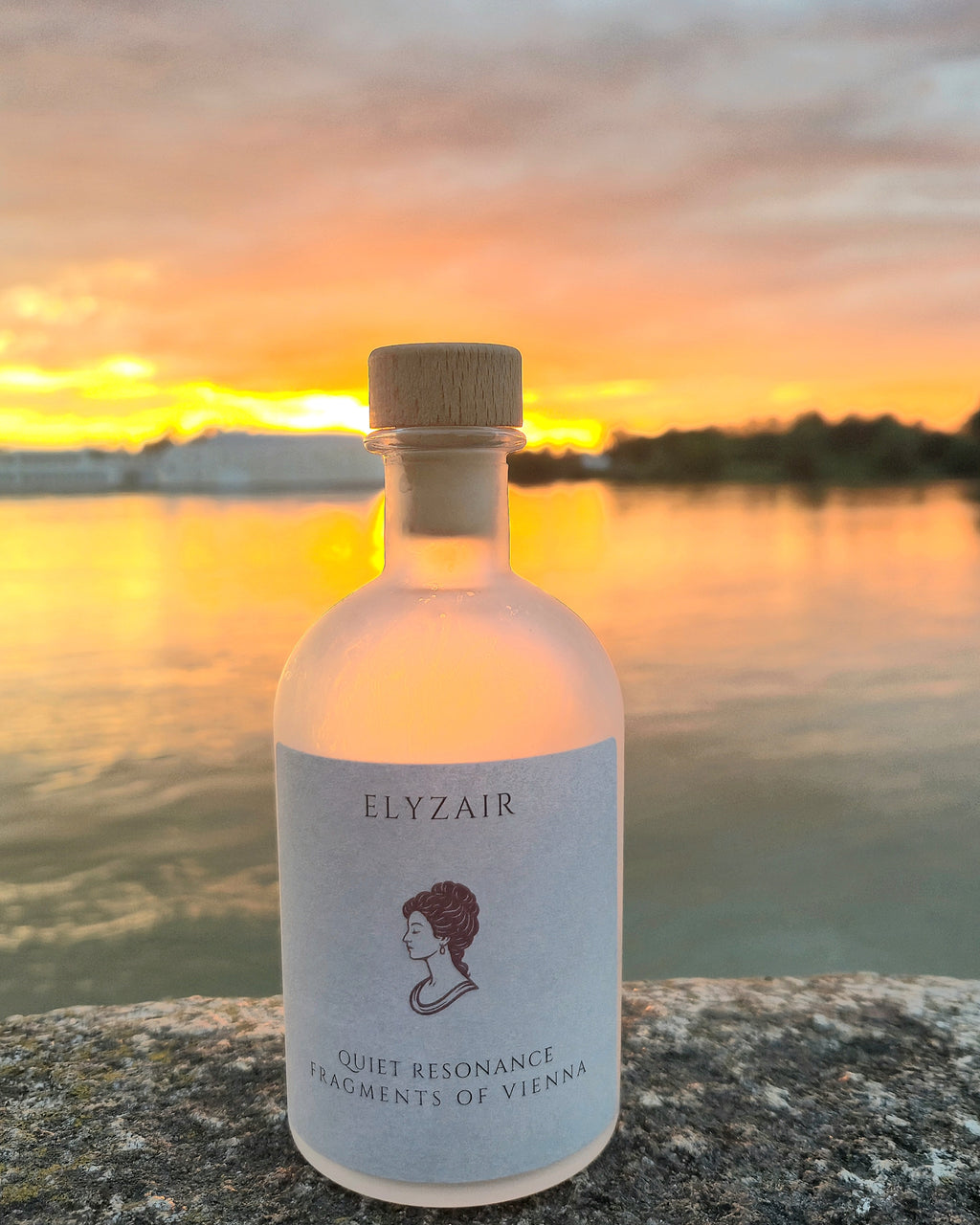ELYZAIR Quiet Resonance, sealed glass edition of Vienna, on a stone ledge above the water at sunrise